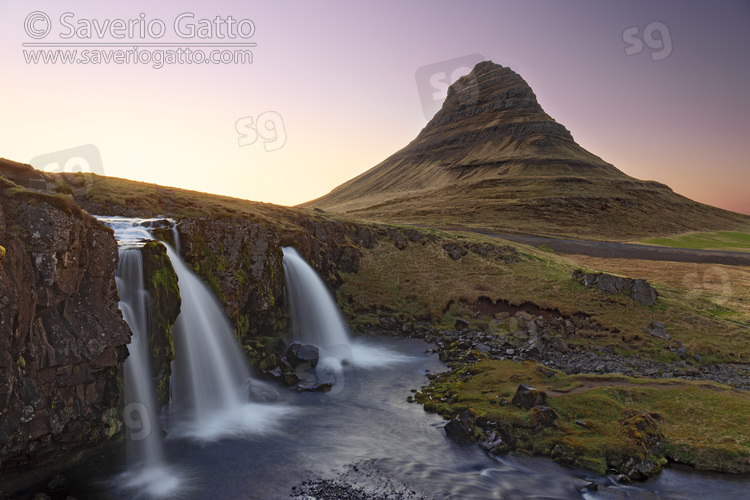 Kirkjufell mountain at sunset, mountain against clear sky and a waterfall in foreground