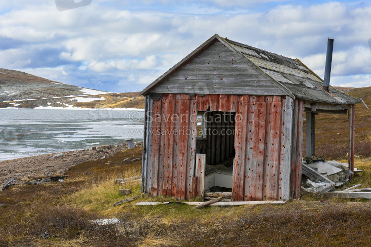 Old House at Batsfjordfjellet, tundra landscape with frozen lake and patches of snow