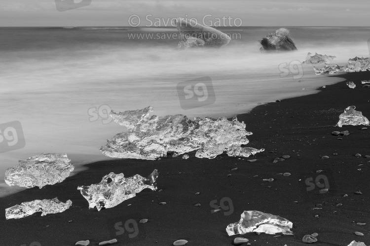 Diamond Beach (Iceland), pieces of ice on the beach with icebergs in the background
