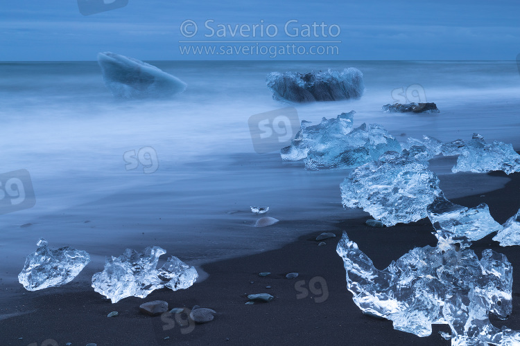 Diamond Beach (Iceland), pieces of ice   on the beach with icebergs in the background