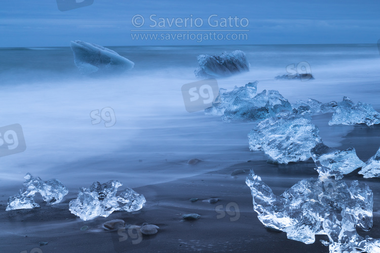 Diamond Beach (Iceland), pieces of ice   on the beach with icebergs in the background